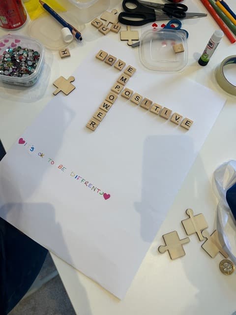 Craft materials and letter tiles spelling LOVE and POSITIVE during a Cuckmere Training session