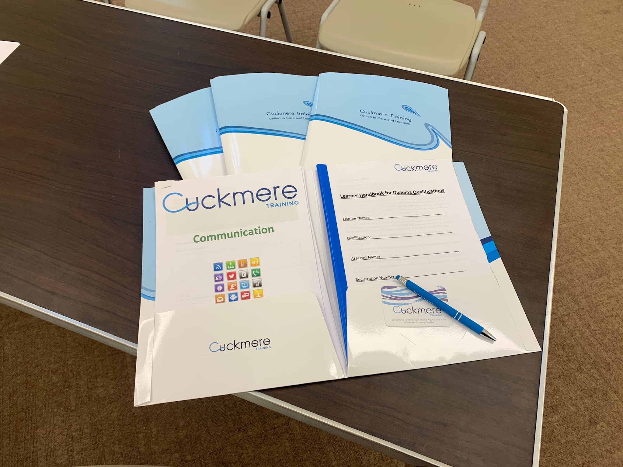 Cuckmere Training course booklets, a learner handbook and a branded pen laid out on a table